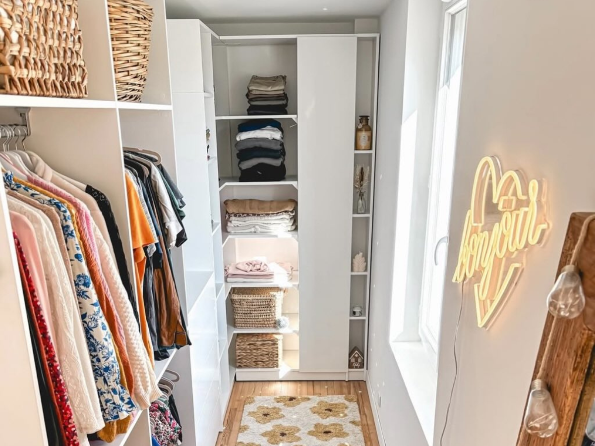 Maßgefertigtes L-förmiges Ankleidezimmer mit Kleiderstangen, festen Regalböden und einer Kommode mit mehreren Schubladen.